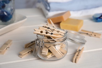 Many wooden clothespins and glass jar on white table