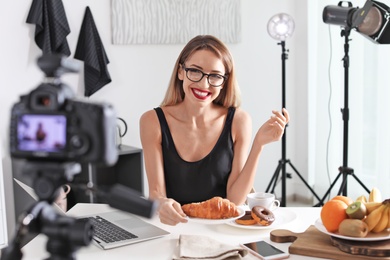 Food blogger recording video on camera at home