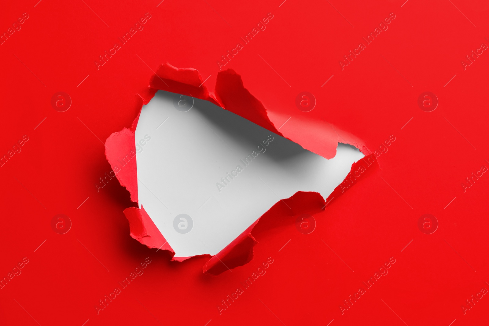 Photo of Hole in red paper on white background