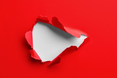 Photo of Hole in red paper on white background