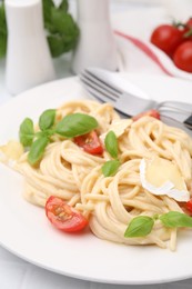 Delicious pasta with brie cheese, tomatoes, basil and cutlery on white table, closeup