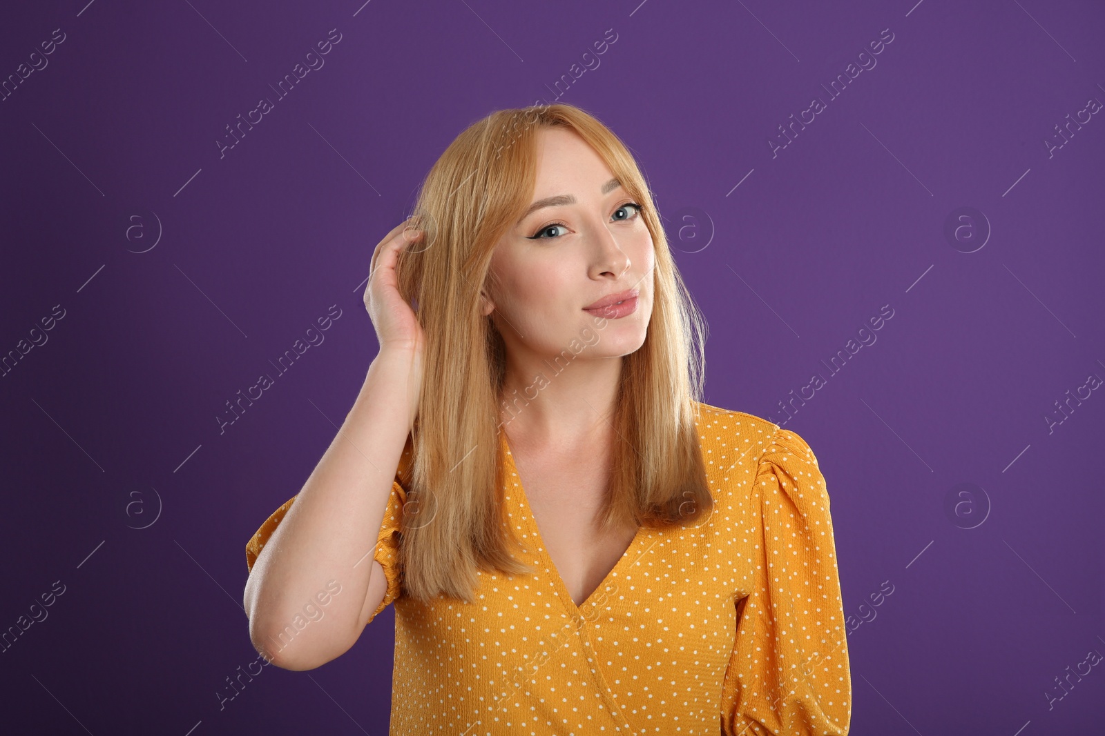 Photo of Beautiful young woman with blonde hair on purple background