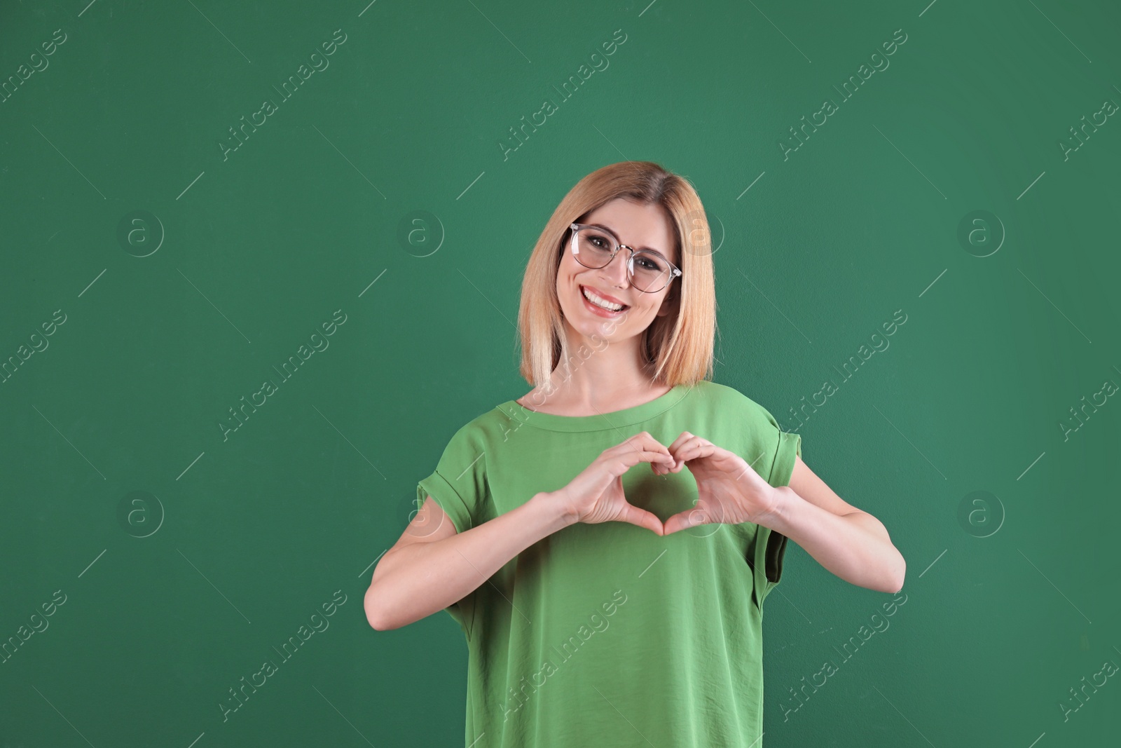 Photo of Portrait of woman making heart with her hands on color background
