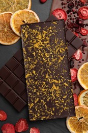 Photo of Different chocolate bars with freeze dried fruits on slate table, flat lay