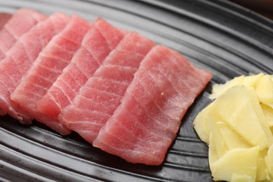 Photo of Tasty sashimi (pieces of fresh raw tuna) and ginger slices on plate, closeup