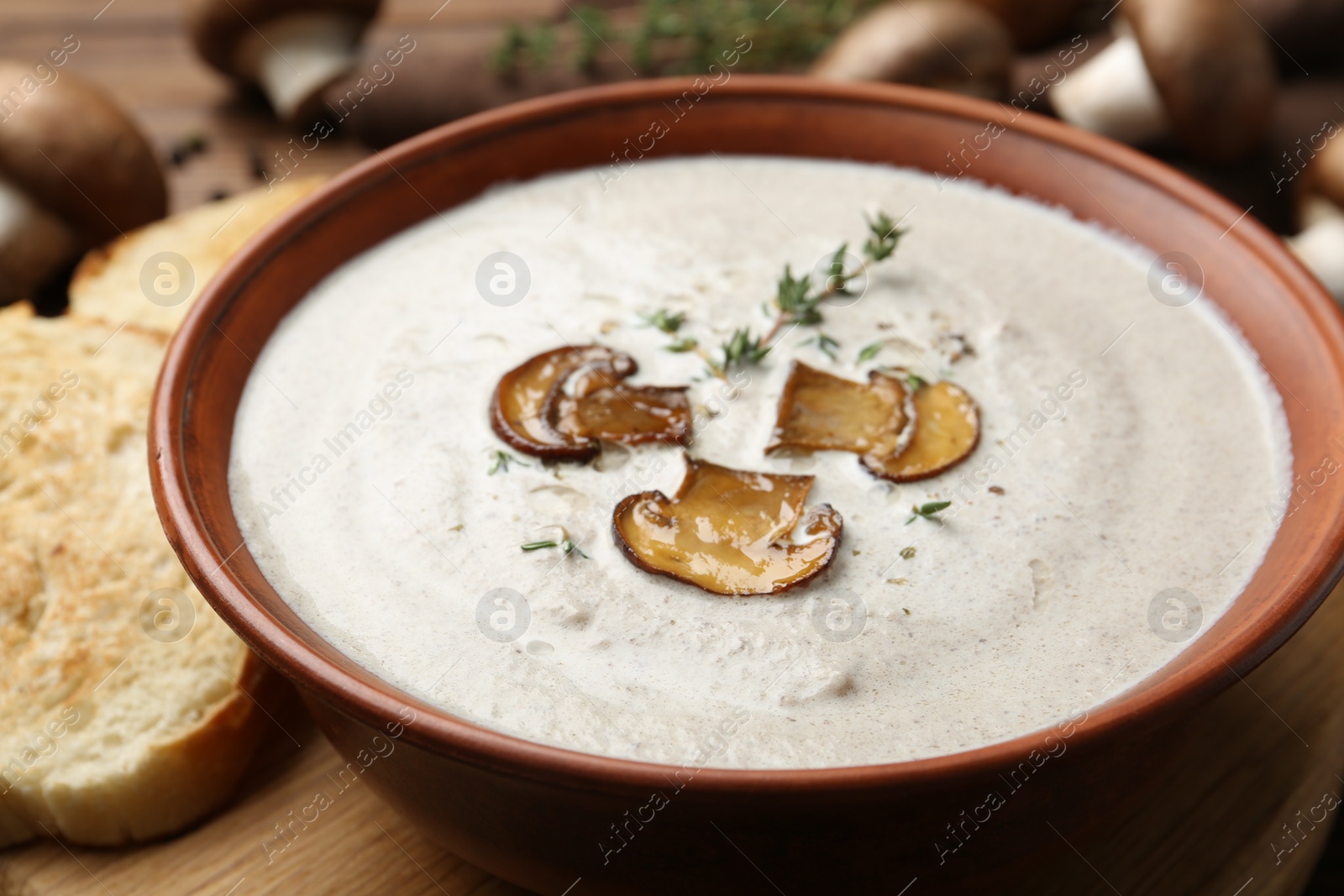 Photo of Fresh homemade mushroom soup in ceramic bowl on wooden table, closeup