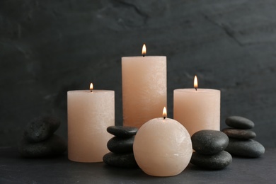 Composition of burning candles and spa stones on table