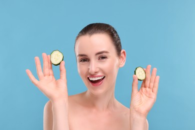 Photo of Beautiful woman with pieces of cucumber on light blue background