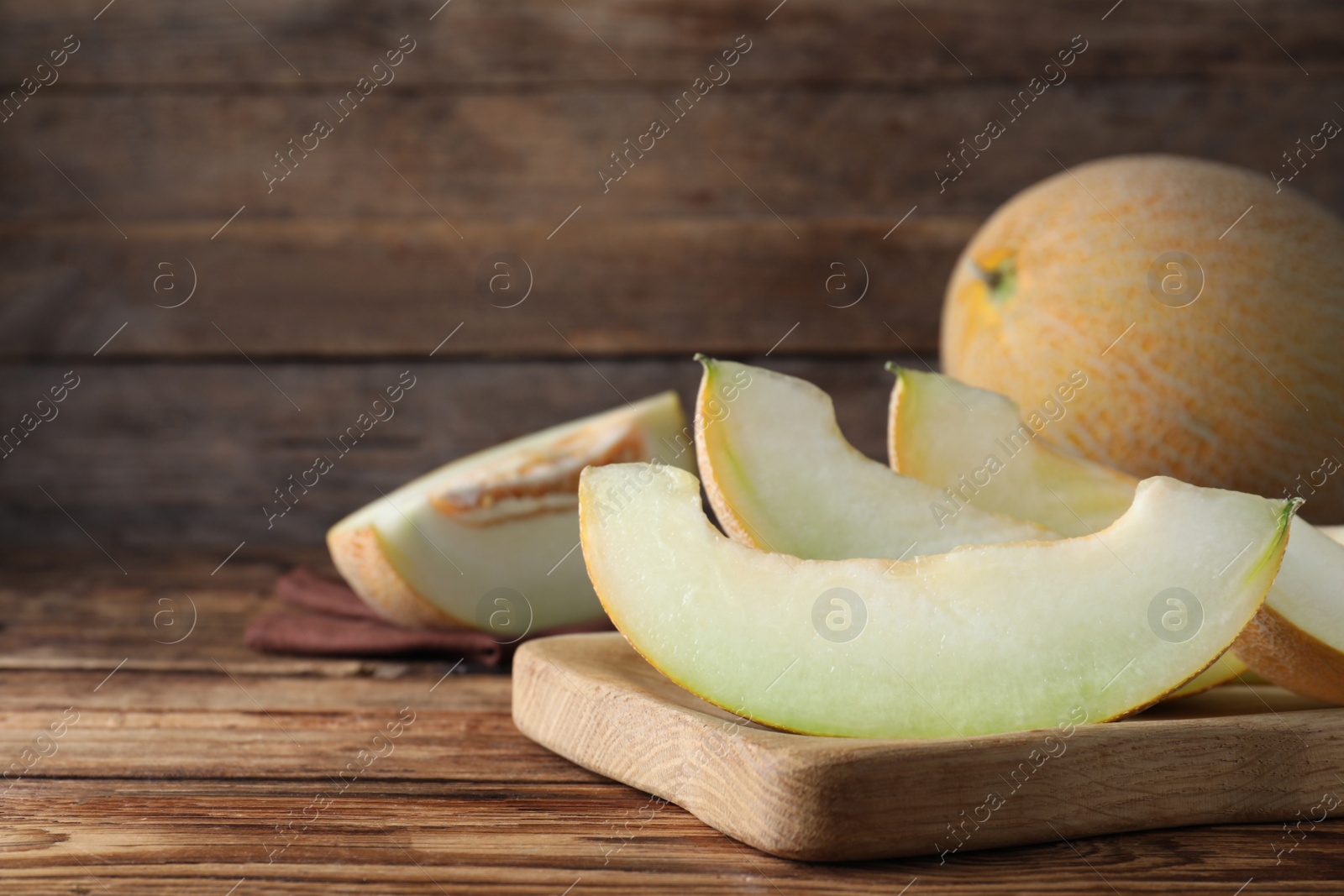 Photo of Pieces of delicious honeydew melon on wooden table. Space for text