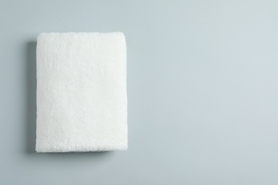 Photo of Soft folded towel on light background, top view with space for text