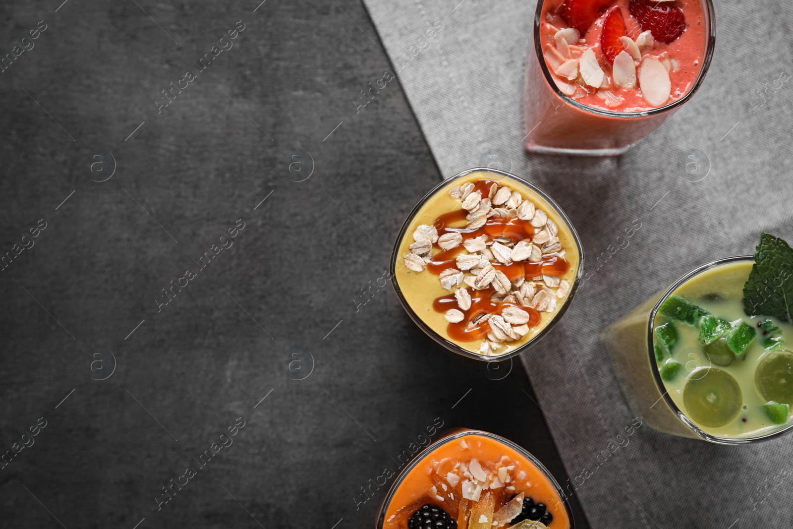 Photo of Many different delicious smoothies on grey table, flat lay. Space for text