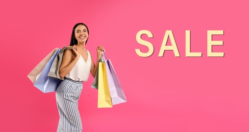 Image of Beautiful young woman with paper shopping bags and word SALE on pink background. Banner design