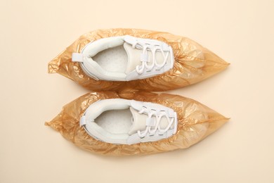 Sneakers in shoe covers on beige background, top view