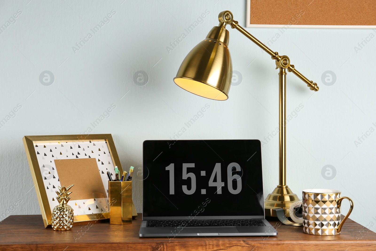 Photo of Modern workplace with laptop and golden decor on desk near wall. Stylish interior design