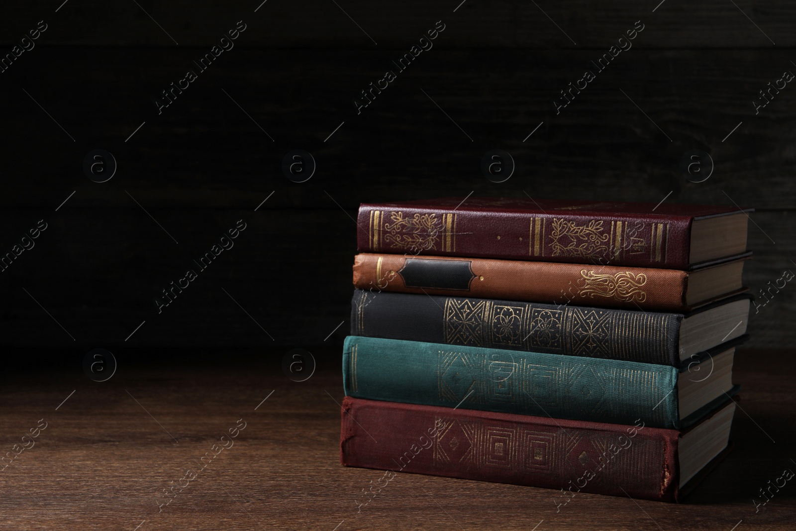 Photo of Stack of old hardcover books on wooden table, space for text