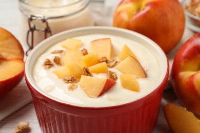Photo of Delicious yogurt with fresh peach and granola in bowl on table, closeup