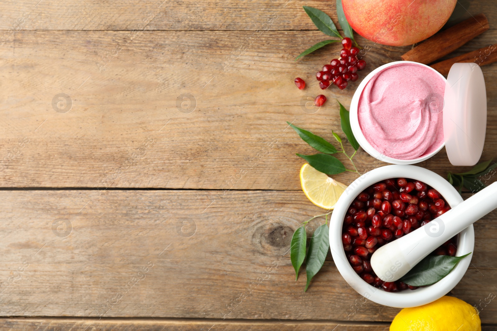 Photo of Flat lay composition with natural homemade mask, pomegranate and ingredients on wooden table. Space for text