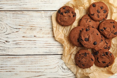 Photo of Delicious chocolate chip cookies on wooden table, flat lay. Space for text