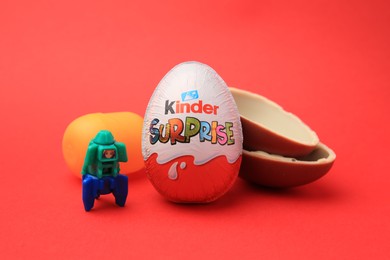 Sveti Vlas, Bulgaria - June 29, 2023: Kinder Surprise Eggs, plastic capsule and toy space rocket on red background