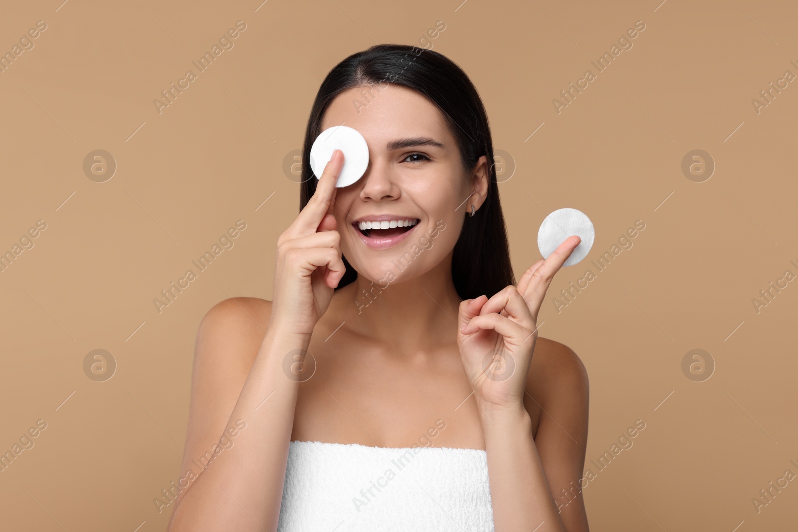 Photo of Young woman with cotton pads on beige background