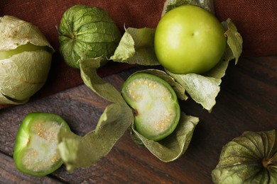 Photo of Fresh green tomatillos with husk on wooden table, flat lay