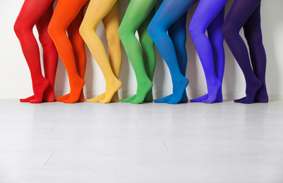 Women wearing colorful tights near white wall, closeup