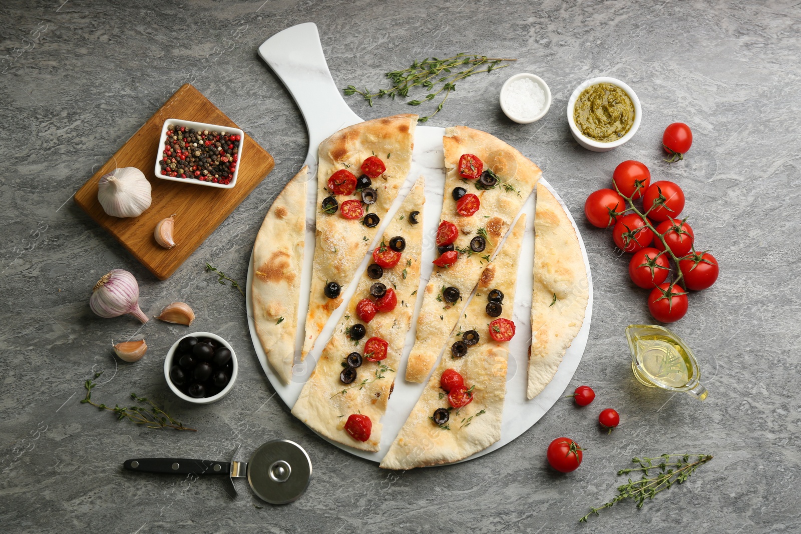 Photo of Delicious focaccia bread with olives and tomatoes on grey table, flat lay