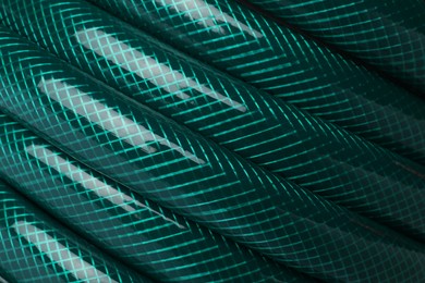 Photo of Green rubber watering hose as background, closeup