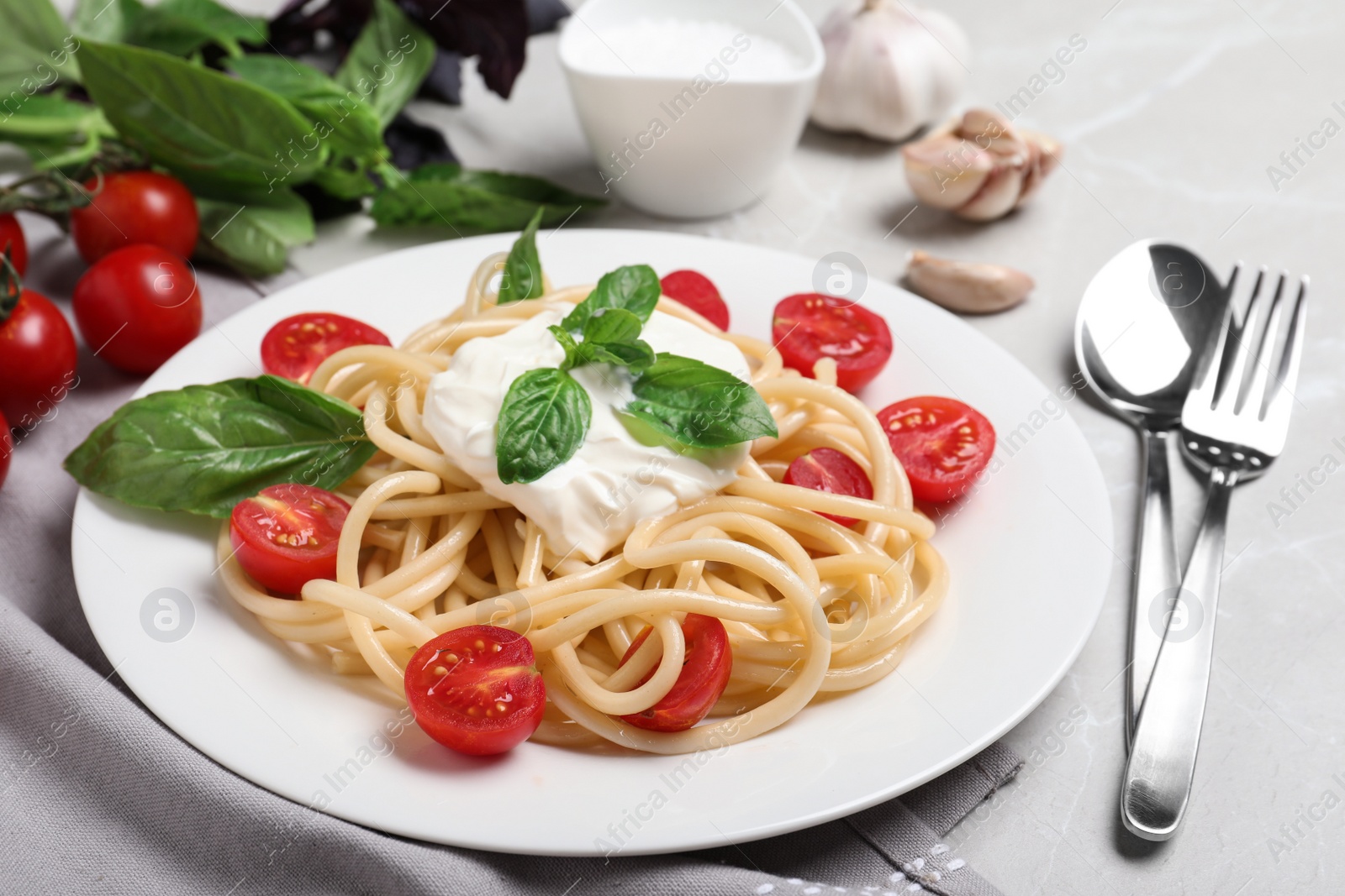 Photo of Delicious spaghetti with sour cream served on grey marble table