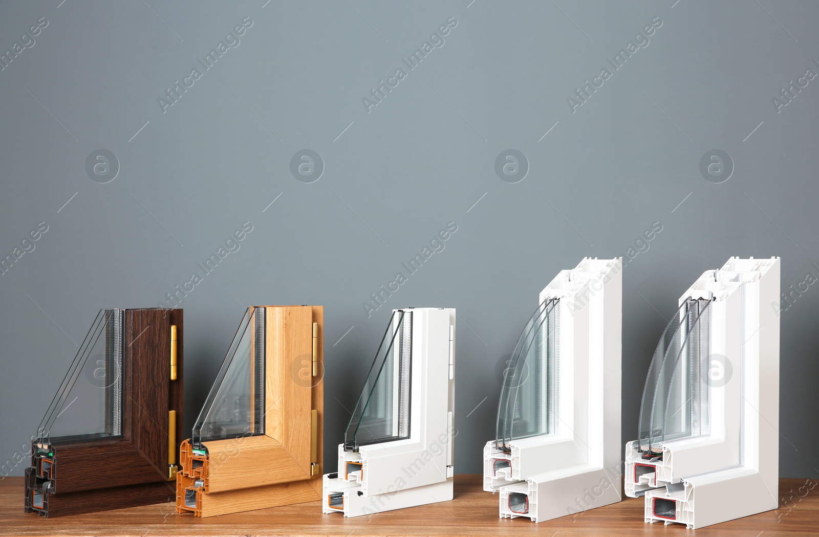 Photo of Samples of modern window profiles on table against gray wall. Installation service