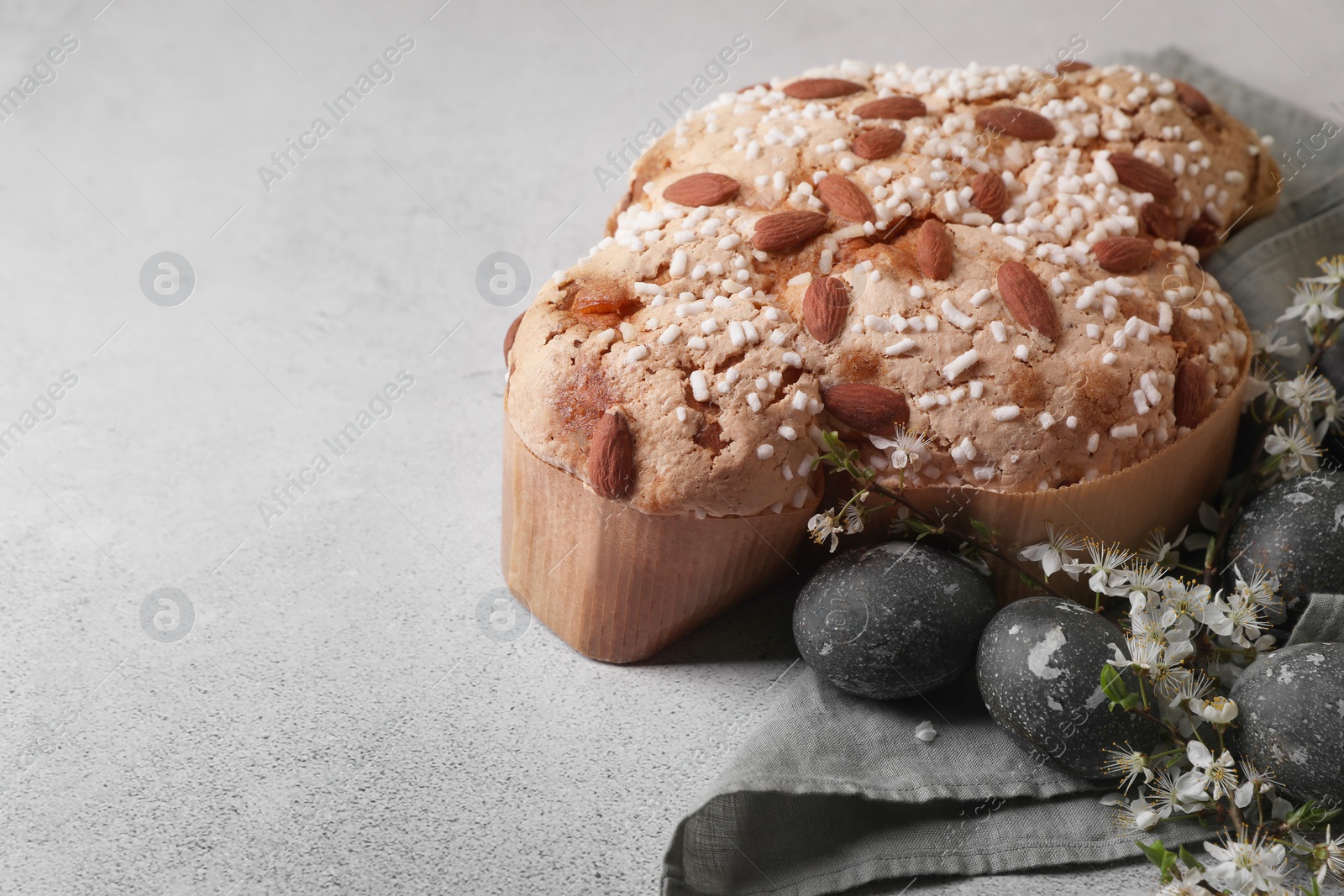 Photo of Delicious Italian Easter dove cake (Colomba di Pasqua), flowers and decorated eggs on grey table. Space for text