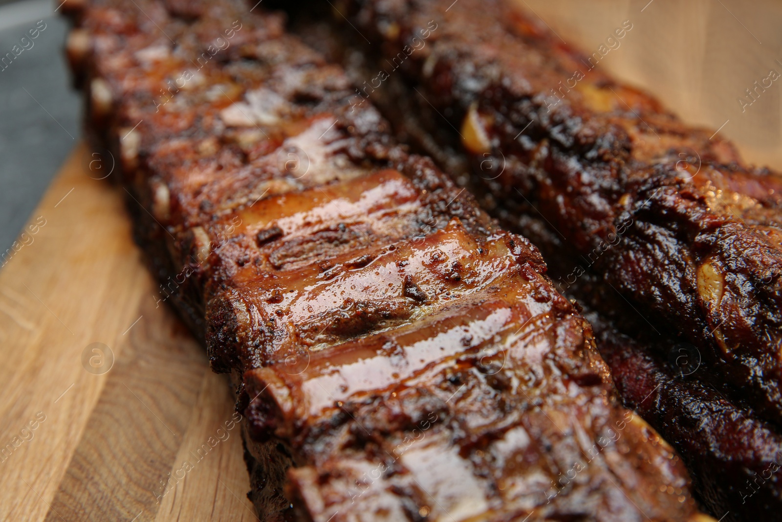 Photo of Tasty grilled pork ribs on wooden board, closeup