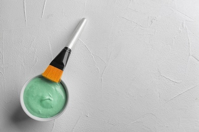 Photo of Spirulina facial mask and brush on white table, flat lay. Space for text