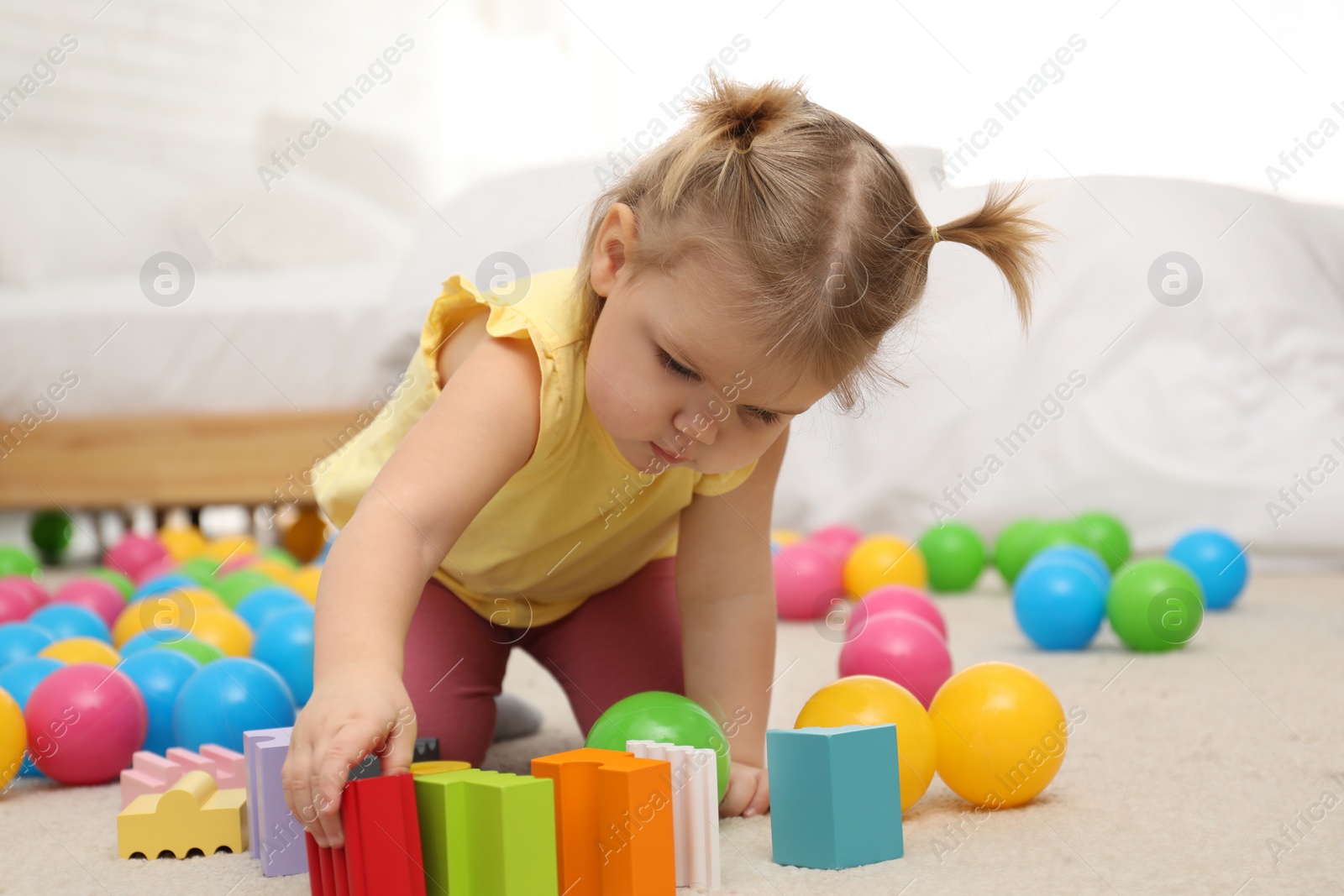 Photo of Cute little child playing with toys on floor at home