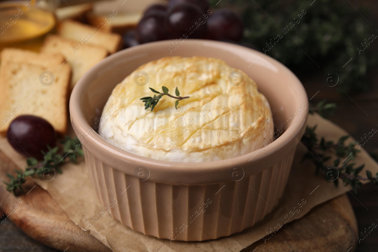 Photo of Tasty baked camembert in bowl on table, closeup