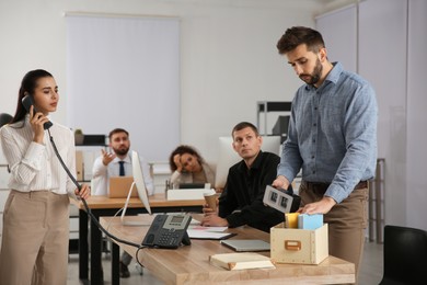 Dismissed man packing stuff into box at office