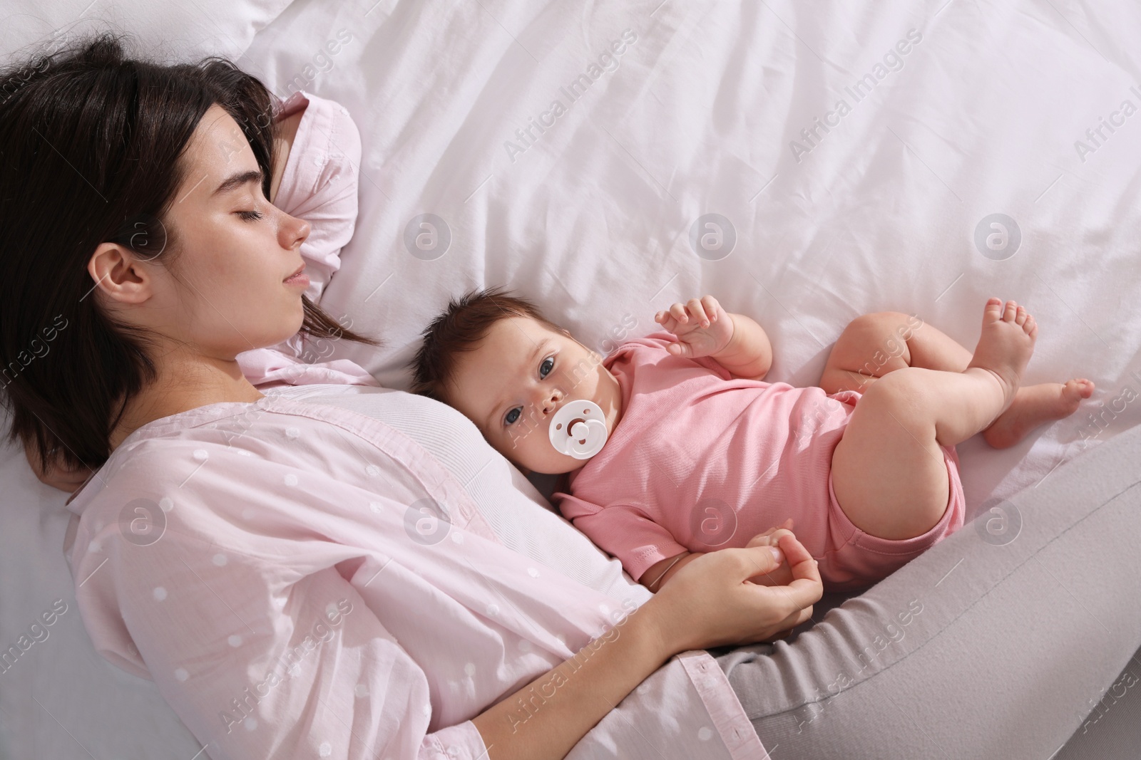 Photo of Young mother sleeping with her baby on bed, top view. Space for text