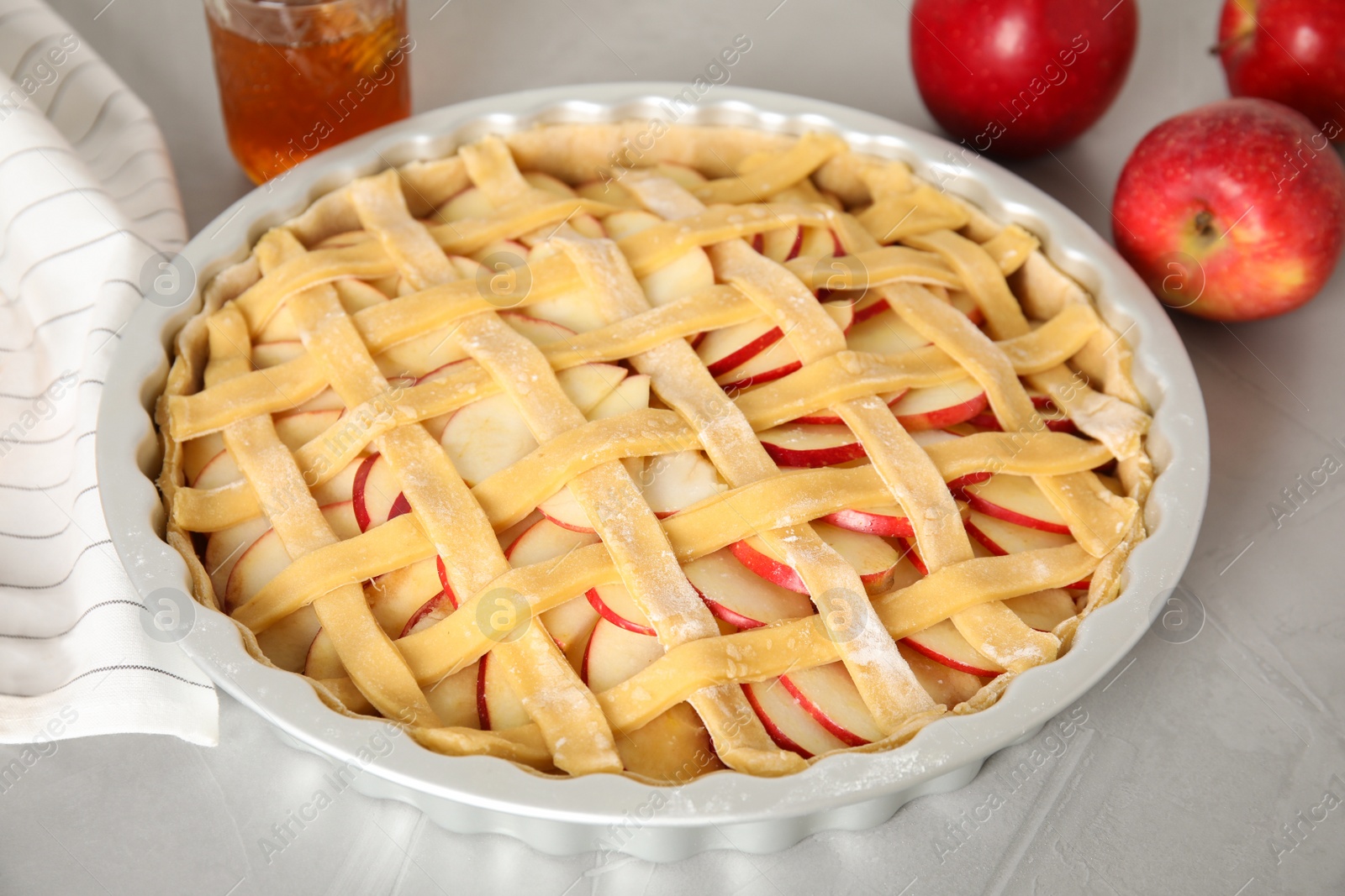 Photo of Raw traditional English apple pie in baking dish on light grey table, closeup