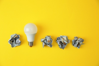 Photo of Flat lay composition with lamp bulb and crumpled money on color background