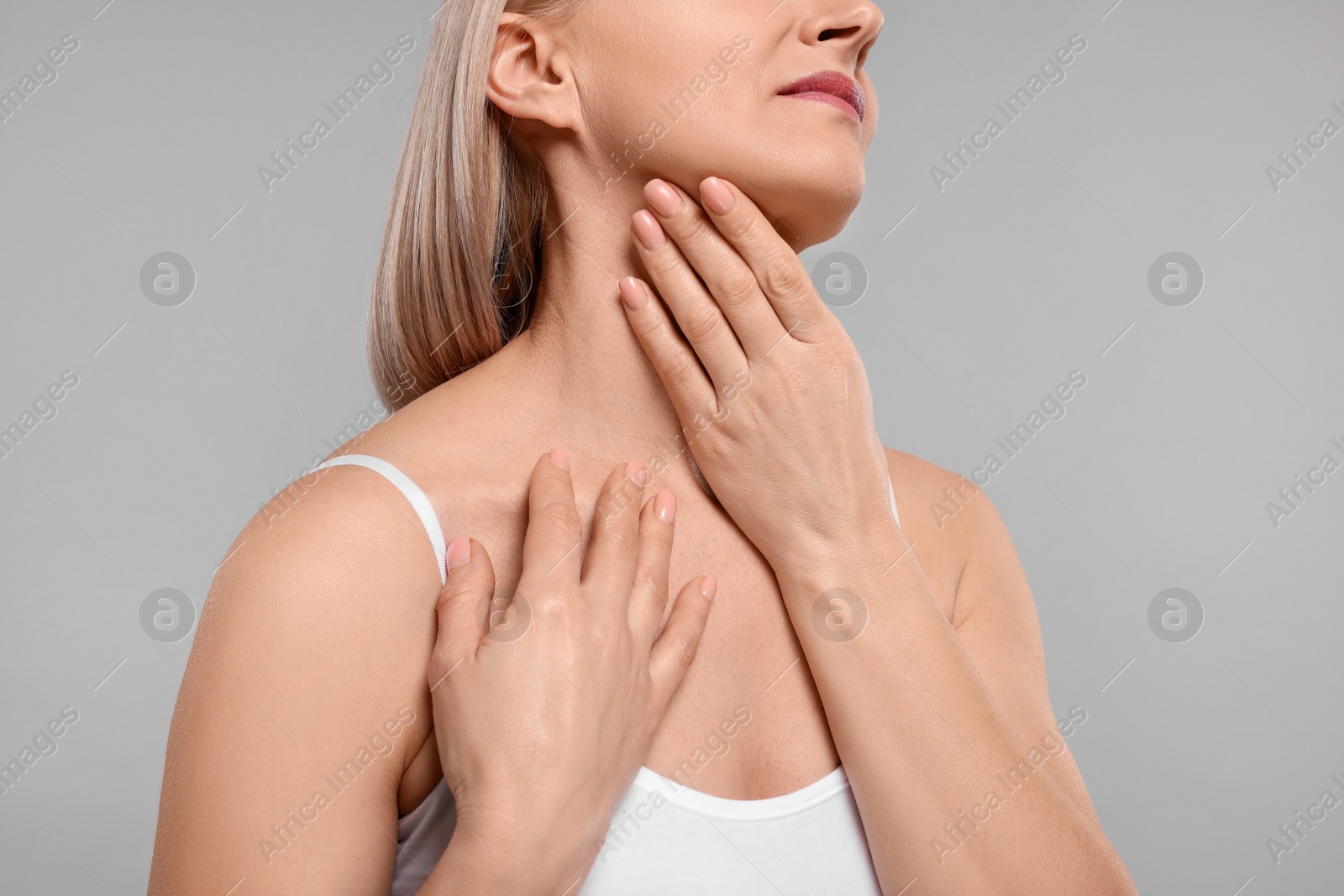 Photo of Woman touching her neck on grey background, closeup