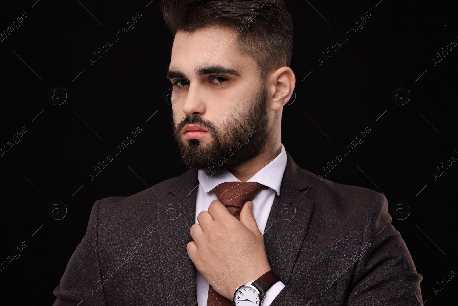 Photo of Handsome businessman in suit and necktie on black background