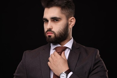 Handsome businessman in suit and necktie on black background