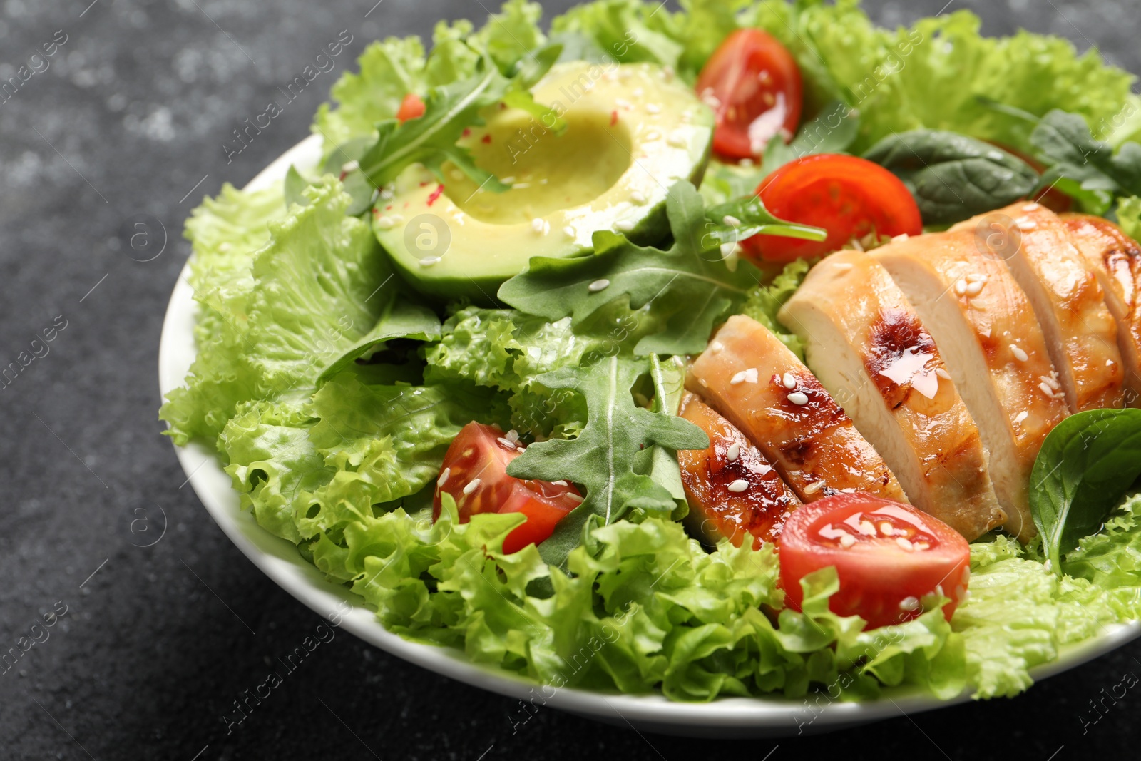 Photo of Delicious salad with chicken, cherry tomato and avocado on grey table, closeup