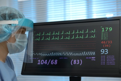 Photo of Nurse near monitor with cardiogram in hospital