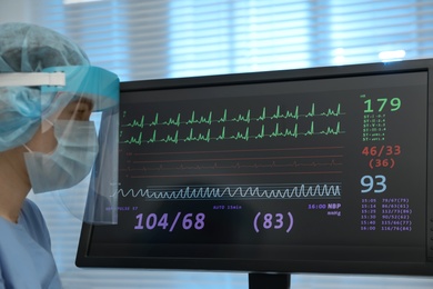 Nurse near monitor with cardiogram in hospital