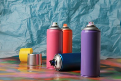 Cans of different graffiti spray paints on color background