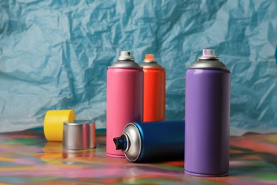 Photo of Cans of different graffiti spray paints on color background