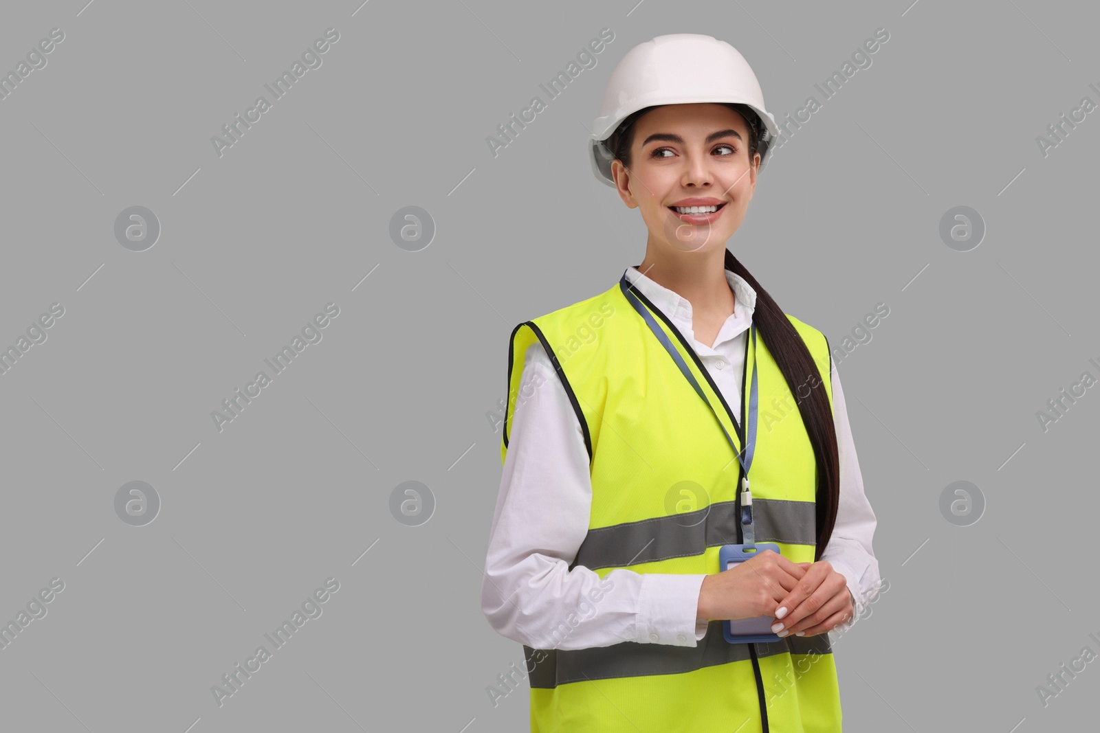 Photo of Engineer with hard hat and badge on grey background, space for text