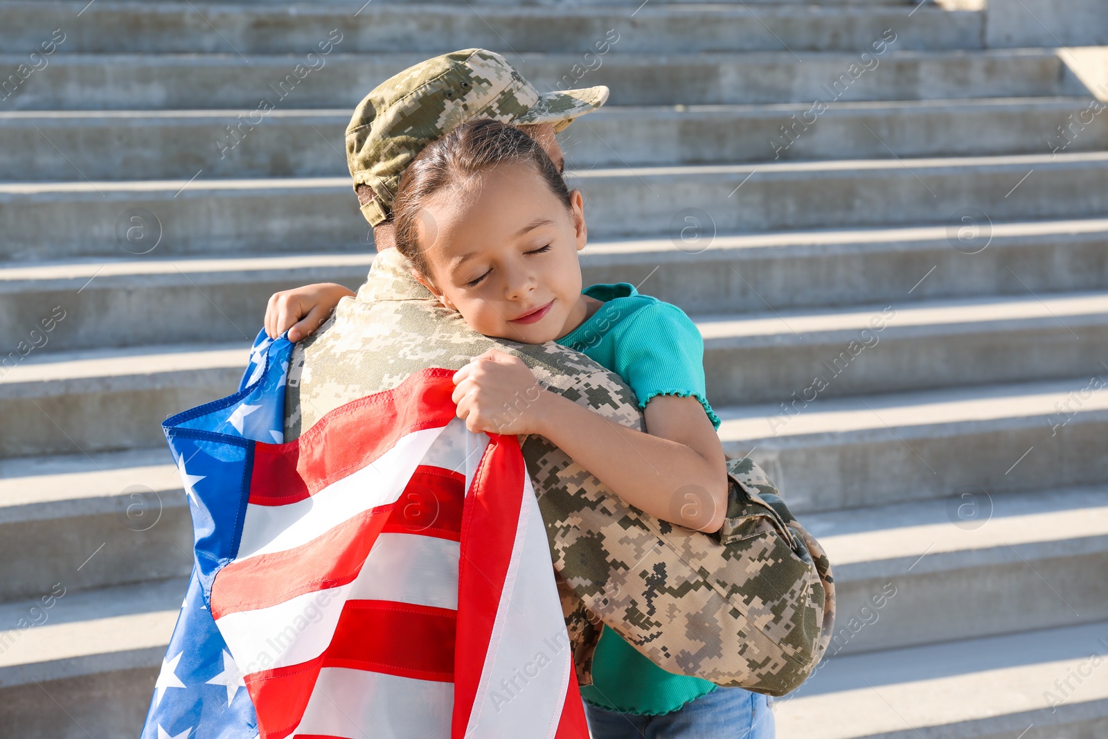 Photo of Soldier with flag of USA and his little daughter hugging outdoors, space for text