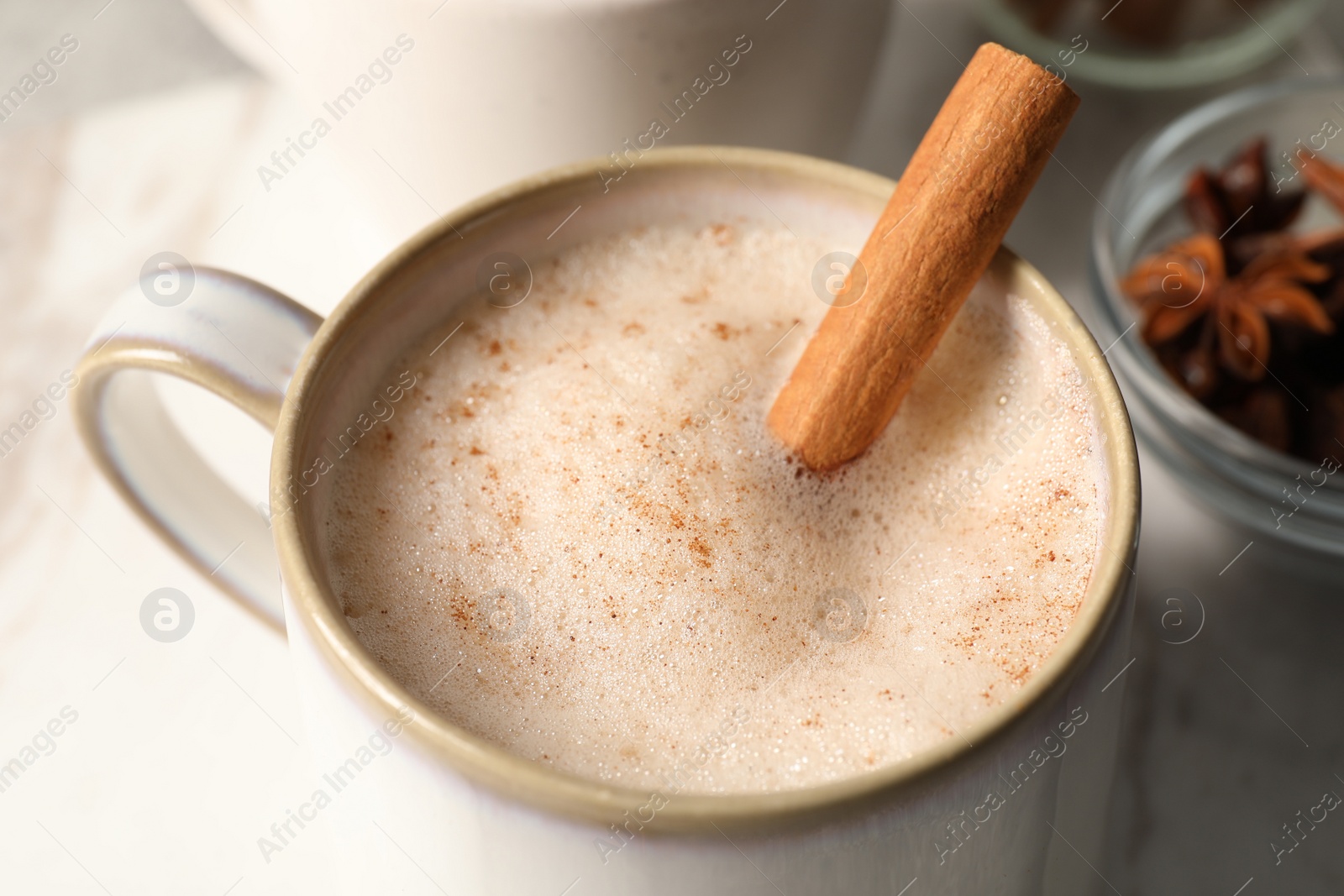 Photo of Cup of delicious eggnog with cinnamon on light grey table, closeup